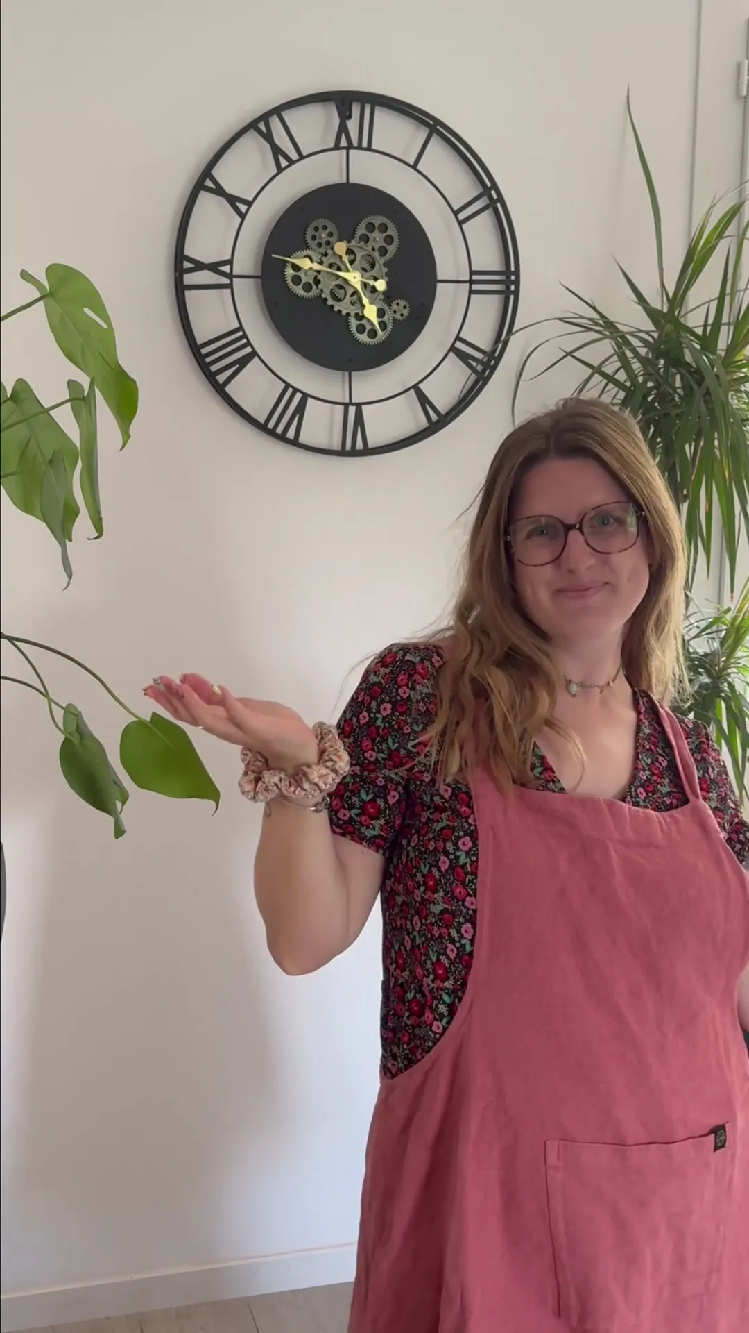 Anaëlle, fondatrice de KILDE, en tablier rose, souriante devant une horloge et des plantes