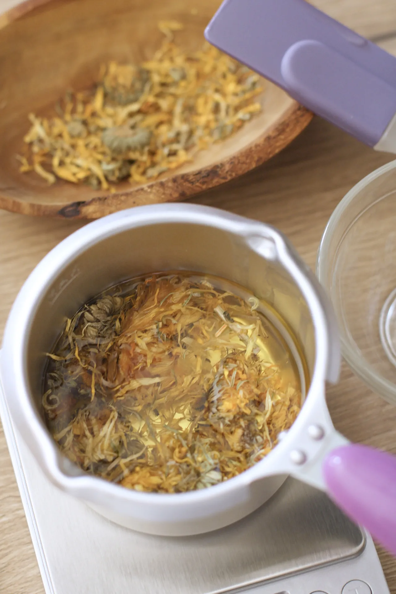 Un macérât de calendula chauffe doucement dans un poêlon, vu de dessus