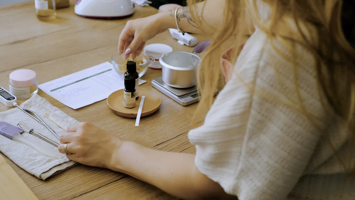Une participante prépare sa formule : fiche de pesée, fiole, balance et spatules sur la table d'atelier