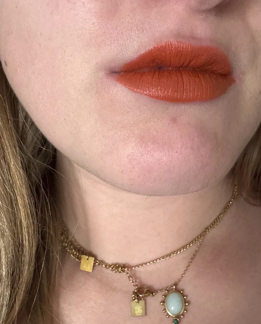Un rouge à lèvres orangé porté, vu de près